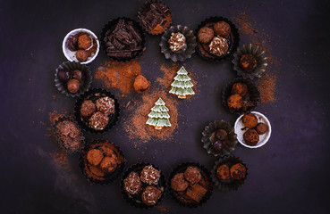 Obraz na płótnie Canvas Christmas wreath composition with chocolate bonbon, different truffles in vintage cupcake molds.