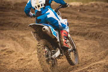 Moto cross - MX girl biker at race in Russia - a sharp turn and the spray of dirt, rear view -...