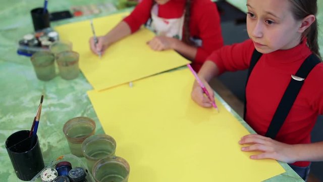 The girl draws a picture paints in classroom