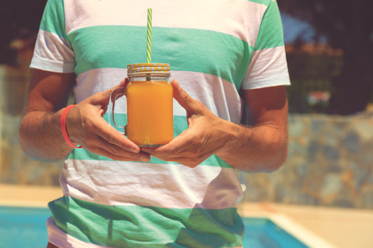 Man holding jar with orange juice.