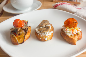 Set of three crostini on white plate.