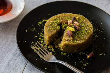Turkish Dessert irmik helvasi with pistachio powder and tea.