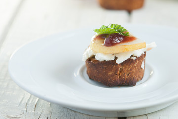 Bruschetta with goat cheese and pear on white plate