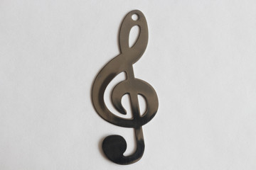 Treble clef, stainless steel on a light background.