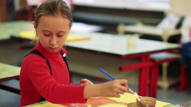 The girl draws a picture paints in classroom