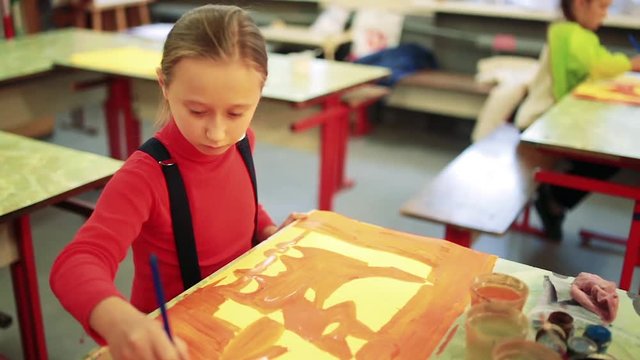 The girl draws a picture paints in classroom
