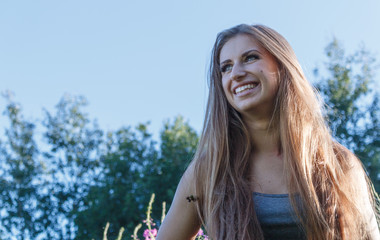 Naklejka premium pretty young woman posing against the backdrop park and smiling.