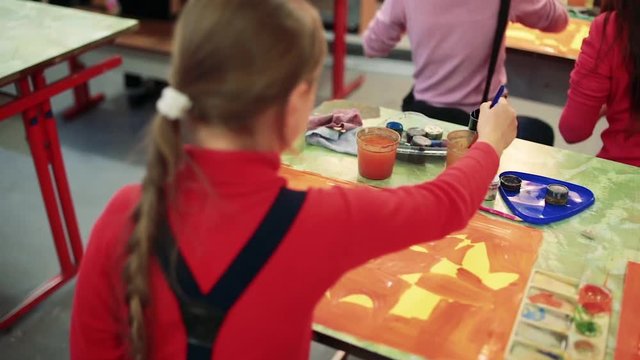 The girl draws a picture paints in classroom
