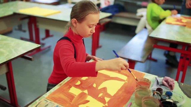 The girl draws a picture paints in classroom