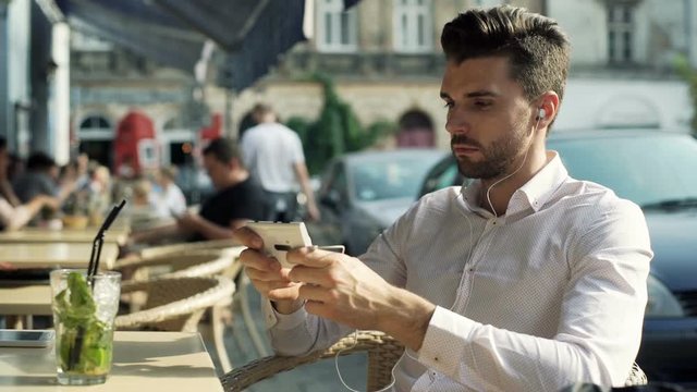 Absorbed man listening music and browsing internet on smartphone
