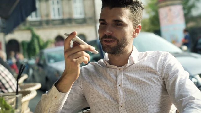 Happy man using loudspeaker while chatting with someone through cellphone

