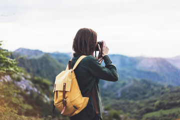 Tourist traveler photographer taking pictures landscape on vintage photo camera on background valley view mockup sun flare, hipster girl with backpack enjoying sunset on peak of foggy mountain