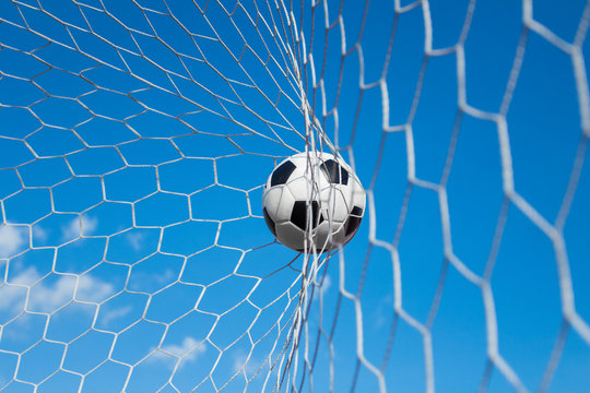 soccer ball in goal net with blue sky