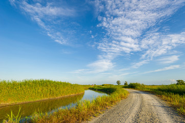 Curvy gravel road and irrigation canal with nice cloudy blue sky