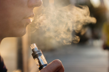 man using vape or electronic cigarette against the background of