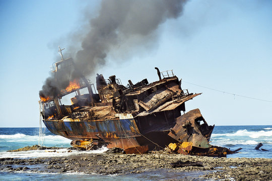 Fototapeta Stranded fish cutter lying burning at a reef.