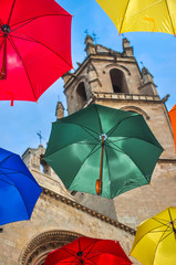 Colorful umbrellas against campanile of gothic basilic.