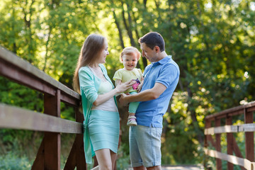 Fototapeta premium Happy family with baby in park on bridge