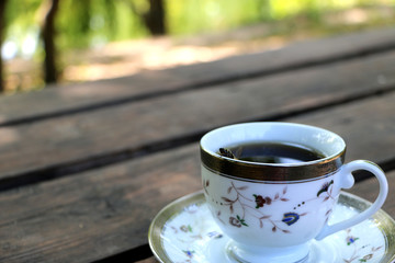 cup full of coffee on the table in nature, the bee in a cup