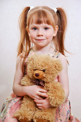 girl with red hair playing with teddy bears