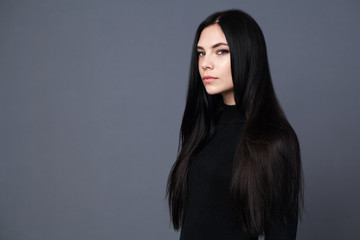 Beautiful brunette girl with gorgeous long hair, gray background