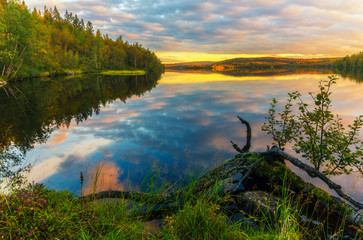 Sunset with colorful clouds over the lake in the autumn forest