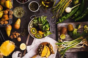 Collection of green vegetables and fruits over dark table. 