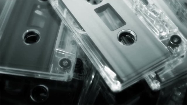 A monochromatic rotating loop of audio cassette tapes rotating on a glass turntable. HD 1080.