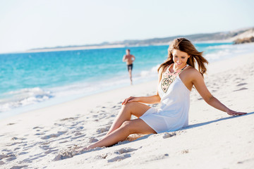 Fototapeta na wymiar Young woman sitting on the beach