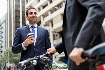 Two young businessmen with a bike in city centre