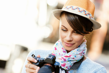 Outdoor summer smiling lifestyle portrait of pretty young woman with camera