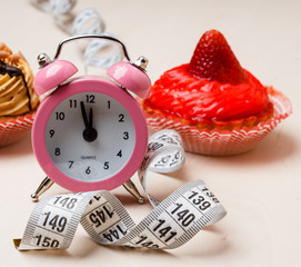 Sweet food measuring tape and clock on table