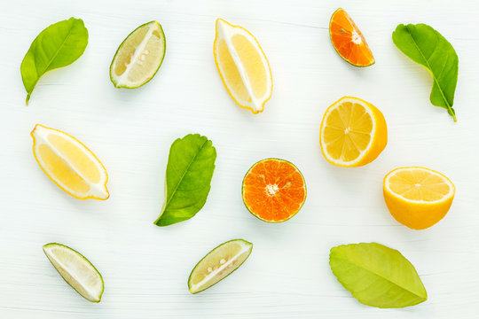 Mixed fresh citrus fruits and leaves background. Fresh lemons, l