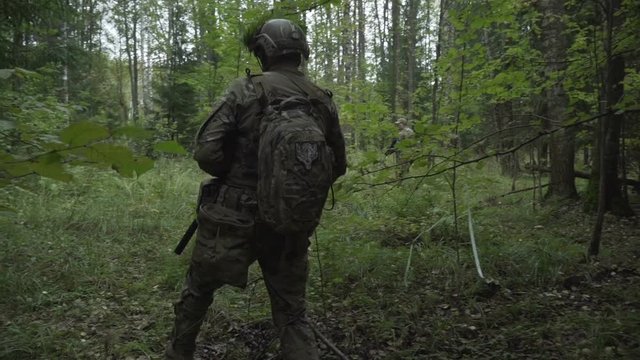 Soldiers go through the woods. Military with arms sent to the thickets of green. airsoft game