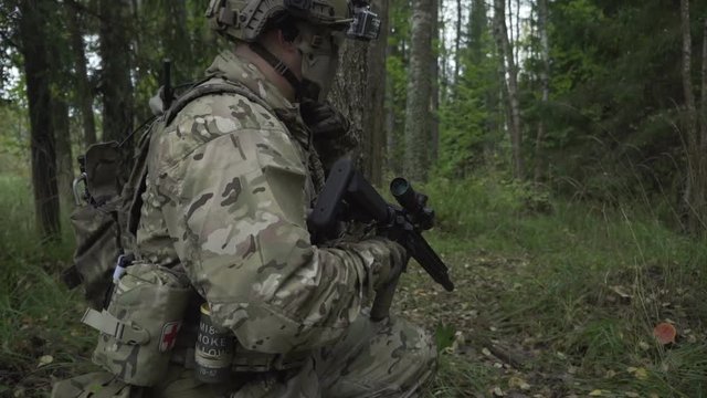 Soldiers go through the woods. Military with arms sent to the thickets of green. airsoft game
