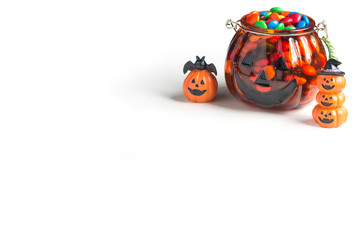 Chocolate candy in Halloween pumpkin glass bucket and Pumpkin Jack on white background.