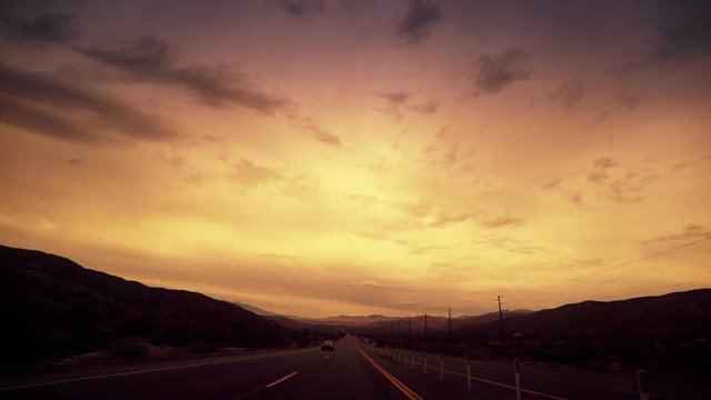 A rear view perspective looking back at highway from a moving car.