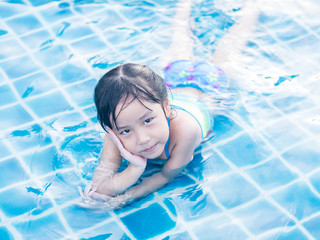 Asian girl is playing in the pool, laying down