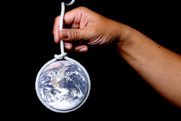 Hand holding a rope with a noose globe.Elements of this image furnished by NASA.