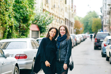 Two happy girls girlfriend walk through the streets of the city