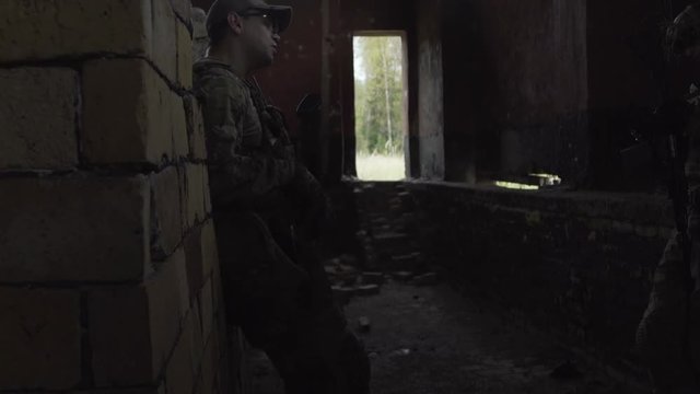 The military are in a ruined building and talk with arms