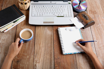 A woman works on a computer desk, book, books, pencils, DVD and coffee table.