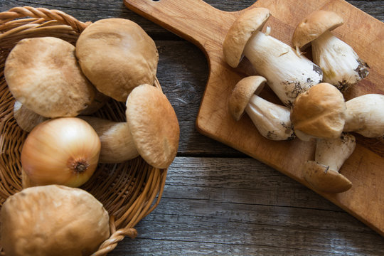 Fresh white mushrooms from  forset in basket on a rustic wooden board, overhead view.