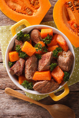 Braised beef with pumpkin closeup in the pan. Vertical top view
