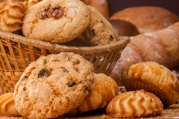 Freshly baked cookies and sweet pastries in the basket on wooden table