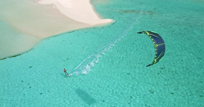Aerial view young man kitesurfing in tropical blue ocean, extreme sport
