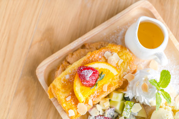 French toast with powdered sugar and a strawberry on wood table