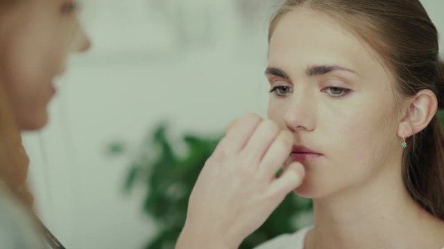 Make-up work. Make-up artist and model. Makeup. Makeup artist applies a primer or foundation using beautyblender. Makeup artist holding sponge for applying foundation