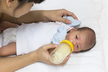 Asian cute new born baby eatting mlik mother in bottle.