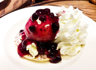 Pancakes with blueberries sauce served with whipping cream